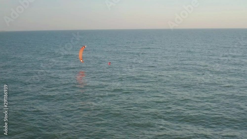 Aerial view of kitesurfer gliding and jumping across ocean