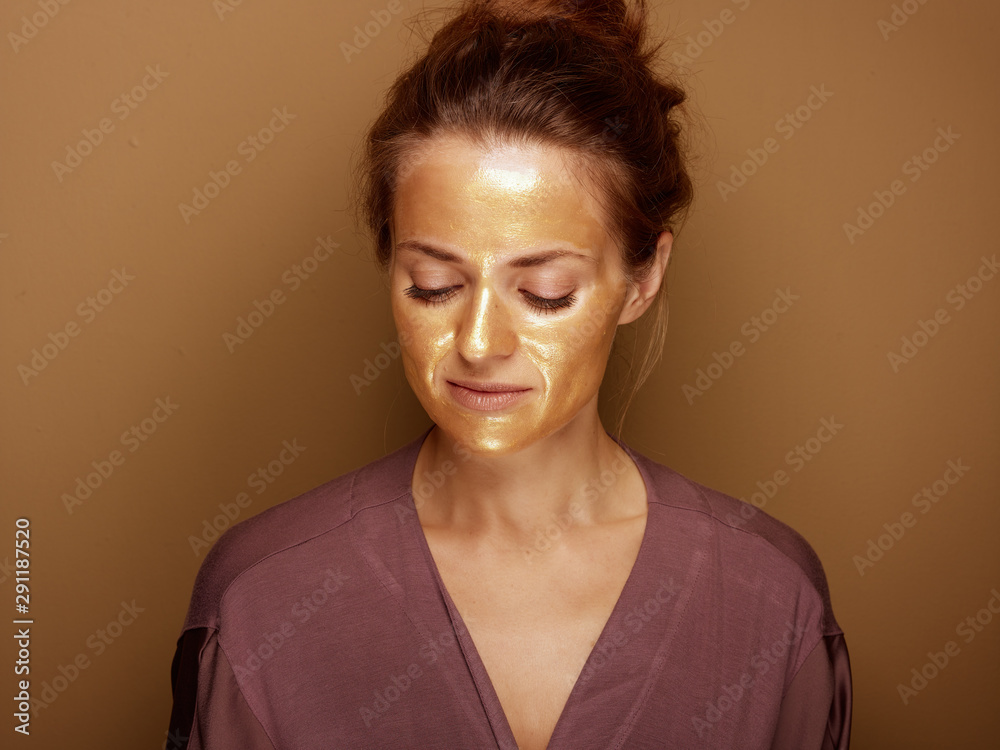 young housewife with golden mask isolated on bronze background