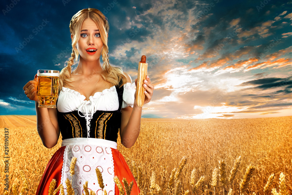 Young sexy Oktoberfest girl waitress, wearing a traditional Bavarian or  german dirndl, serving big beer mugs with drink and french hot dog outdoor.  foto de Stock | Adobe Stock
