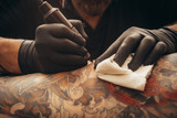 Close up tattoo machine. Tattooing. Man creating picture on his back by a professional tattoo artist.