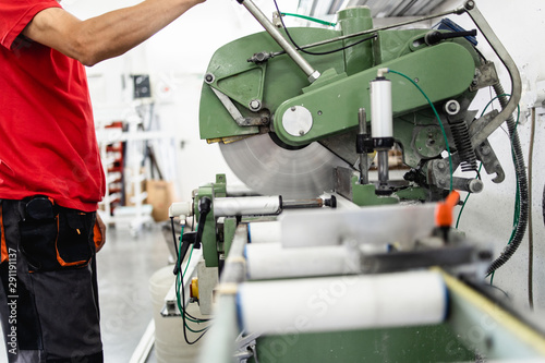 Manual worker cutting aluminum and PVC profiles. Manufacturing jobs. Selective focus. Factory for aluminum and PVC windows and doors production.