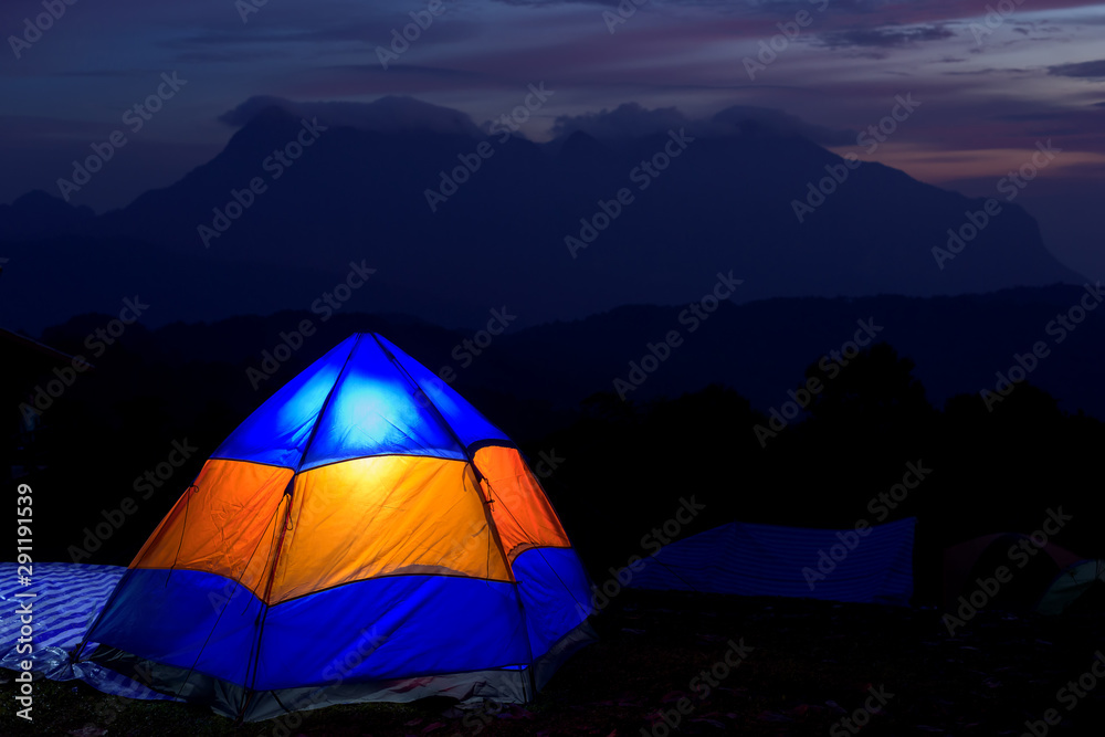 Illuminated Yellow and blue Camping tent at Night.