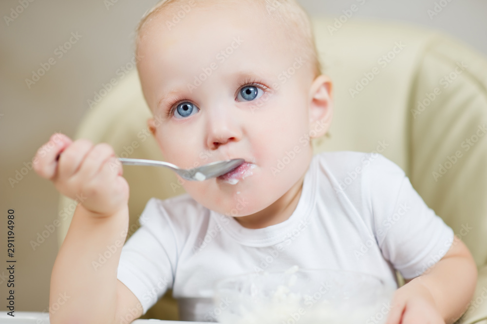 baby girl eats porridge and looks dreamily in front of herself. baby girl eats porridge and looks dreamily in front of herself.
