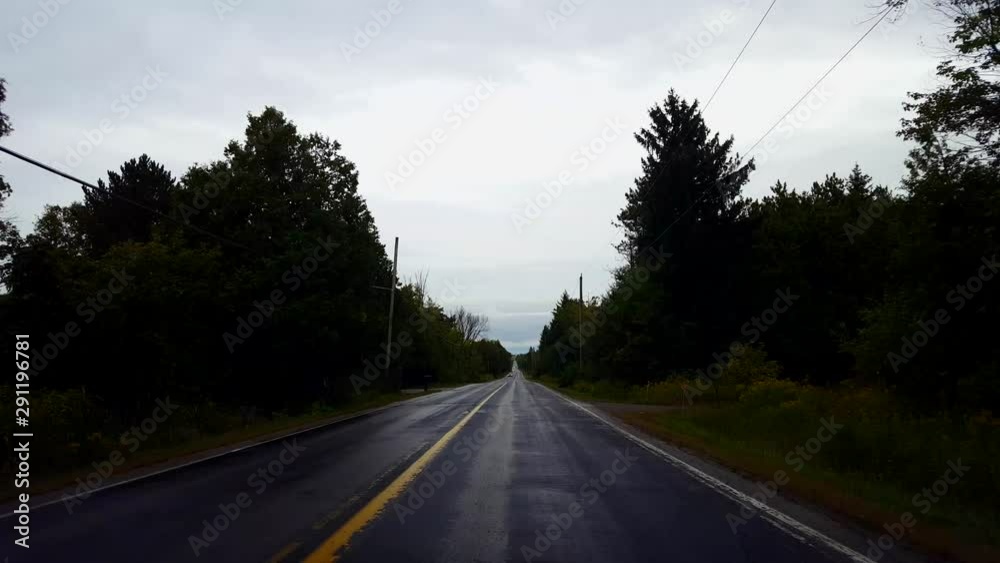 Driving Rural Countryside Wet Road Under Overcast Cloudy Sky in Day. Driver Point of View POV After Dark Rain Storm With Water on Street. Driving Rural Countryside Wet Road Under Overcast Cloudy Sky in Day. Driver Point of View POV After Dark Rain Storm With Water on Street.
