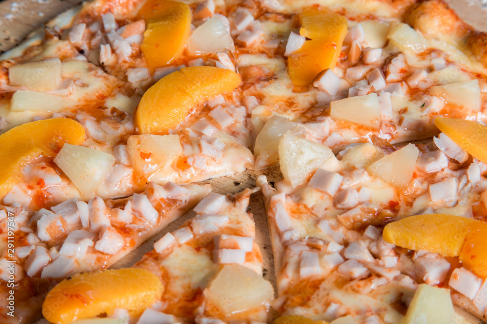 hawaiian pizza with ham and pineapples on a wooden platehavaian pizza with ham and pineapples on a wooden plate