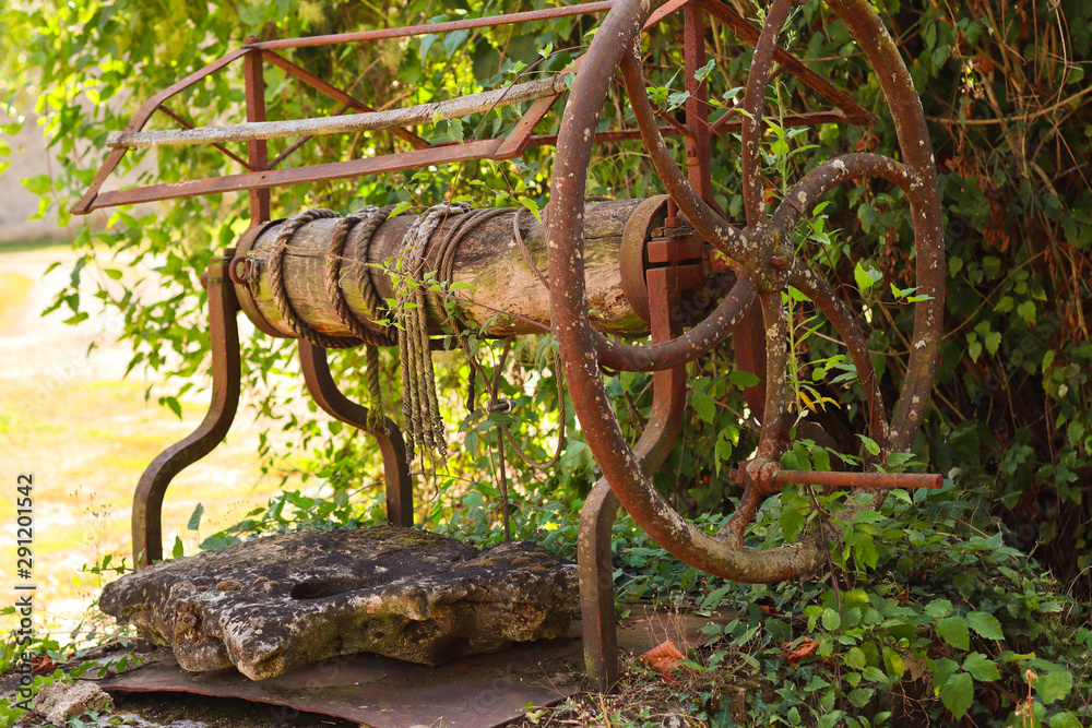 Old abandoned water well with rusty wheel in the village. Rustic background Old abandoned water well with rusty wheel in the village. Rustic background