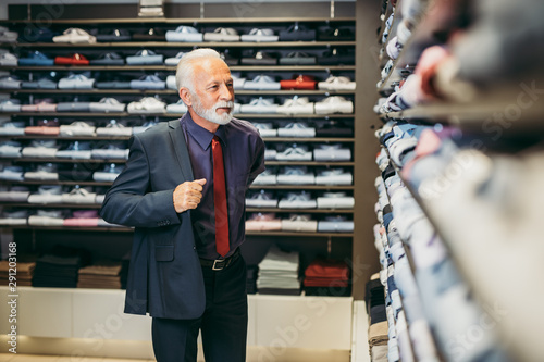Stylish and modern senior business man choosing and buying suite in expensive store.