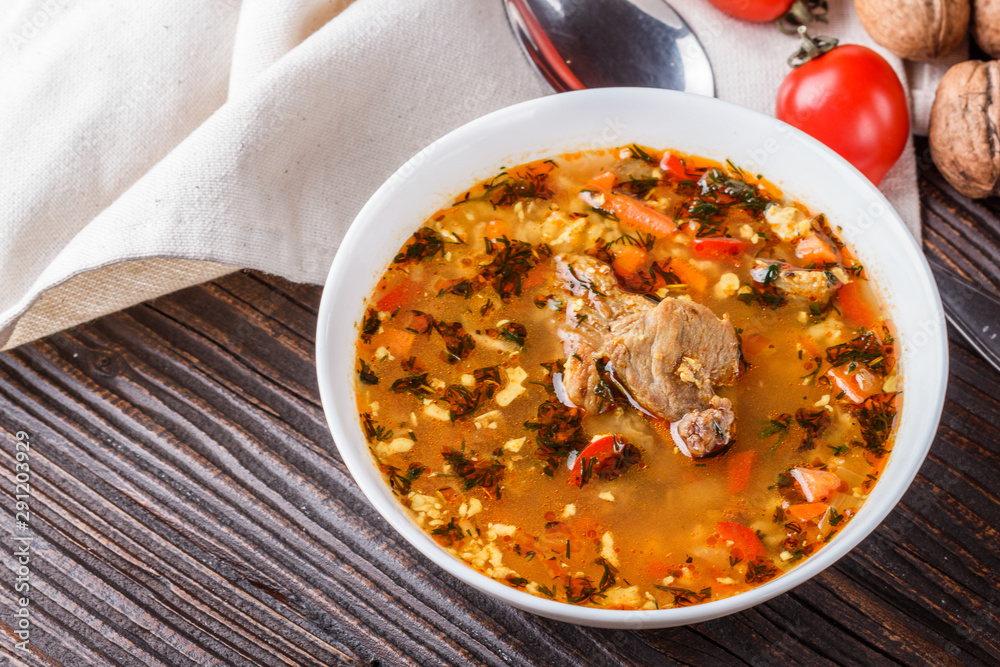 Georgian soup. Kharcho with rice, tomato, beef, garlic and herbs in bowl on wooden table Georgian soup. Kharcho with rice, tomato, beef, garlic and herbs in bowl on wooden table