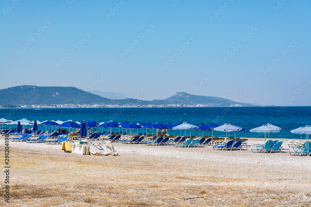 Multicolored umbrellas and sunbeds await tourists on the beach for relaxation and sunbathing. Multicolored umbrellas and sunbeds await tourists on the beach for relaxation and sunbathing.