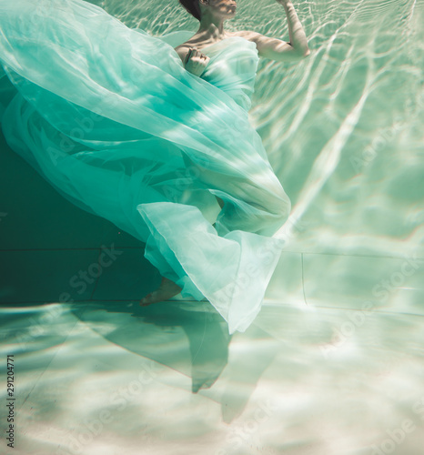 cute bride in light blue long dress swimming underwater on vacantions photo