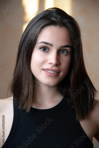 beautiful young brunette caucasian girl portrait, looking at the camera, with a confident happy smile