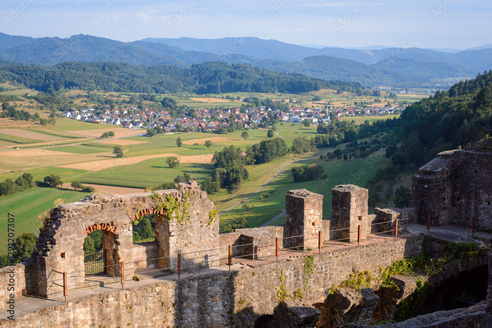 Beautiful landscape of dilapidated castle ruin against small village in Germany in the evening