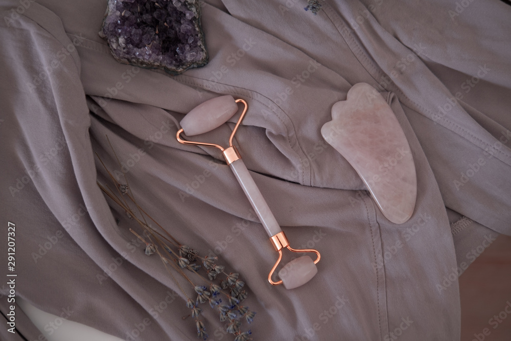 Rose quartz guasha stone and roller. Beauty anti-ageing concept. Top view - obrazy, fototapety, plakaty 