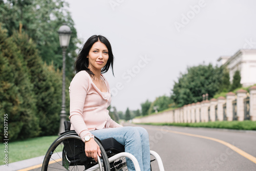 young disabled woman in wheelchair smiling and looking at camera