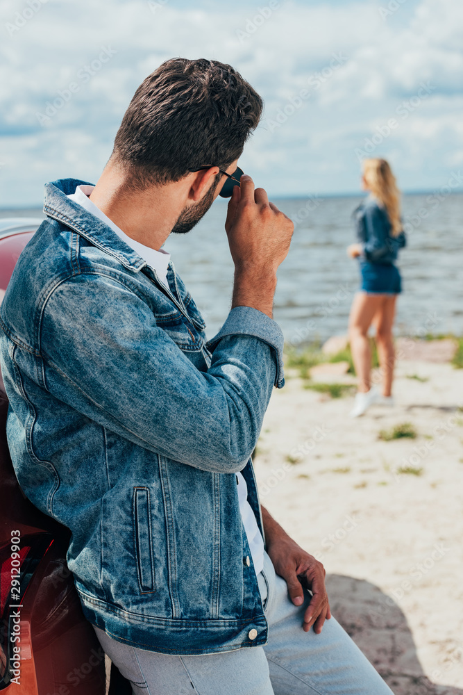 back view of man in jacket and sunglasses looking at woman