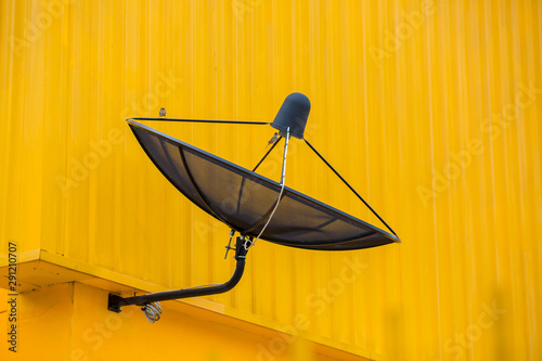 Fototapeta Naklejka Na Ścianę i Meble -  black satellite communication disk on yellow wall building background.