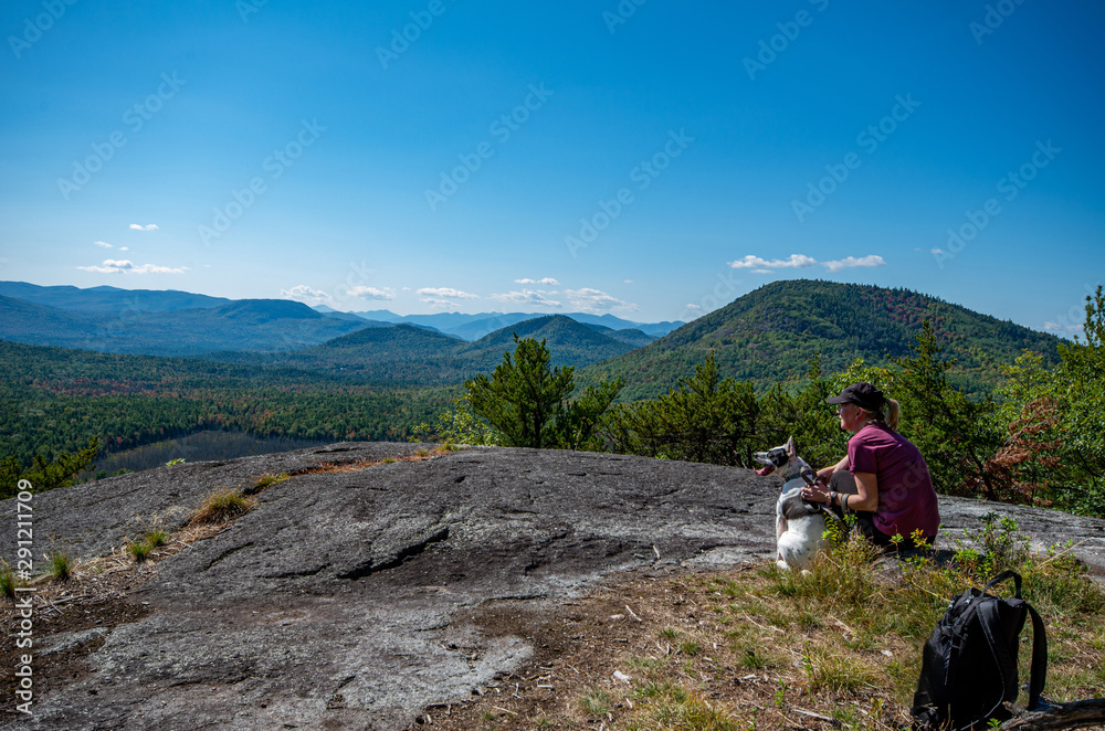 Woman and dog enjoying the view of Adirondack mountain range from the summit of Clark Mountain