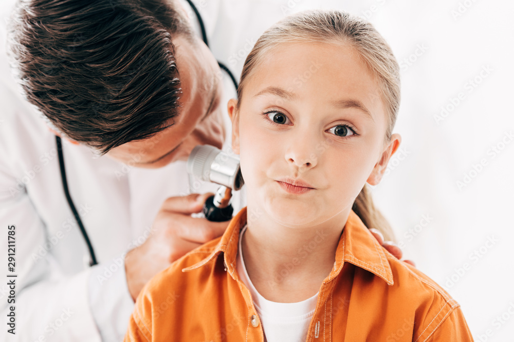 focused pediatrist in white coat examining child with dermascope on white focused pediatrist in white coat examining child with dermascope on white