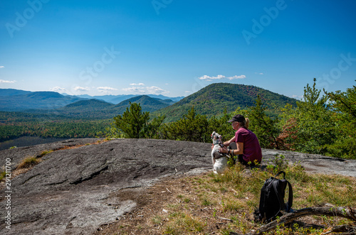 Woman and dog enjoying the view of Adirondack mountain range from the summit of Clark Mountain