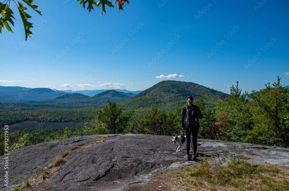 Woman and dog enjoying the view of Adirondack mountain range from the summit of Clark Mountain
