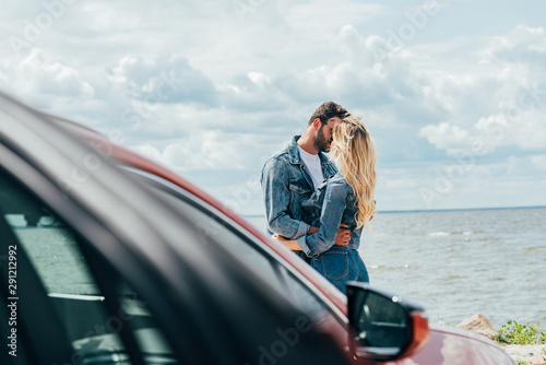 selective focus of woman and man in denim jackets kissing outside