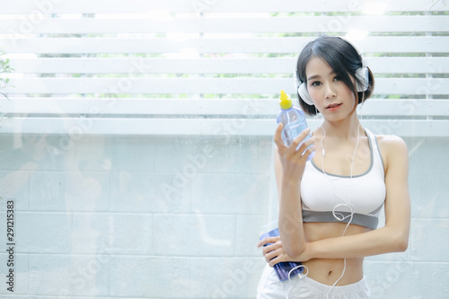 Healthy woman standing holdding water bottle and showing her beautiful body in home on pink backgrounds, Healthy concept, Diet concept