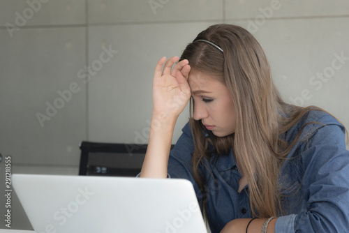 young woman with laptop.Feeling tired and stressed. Frustrated young woman keeping eyes closed and massaging nose while sitting at her working place in office.
