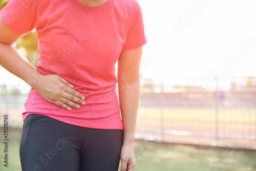 Young woman is suffering stomach pain from running or workout, pain and colic is a frequent problem while running or workout.