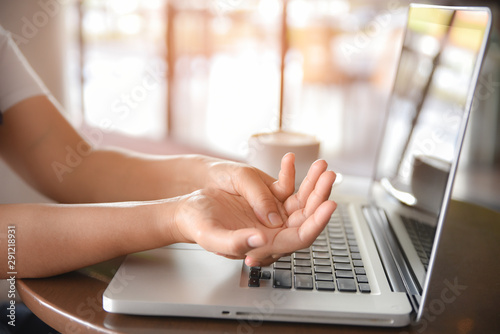 Woman holding her hand pain from using computer long time. Office syndrome concept.