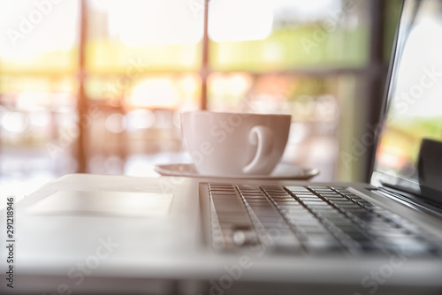 Laptop and coffee cup on blurred coffee shop or cafe, restaurant background, Selective focus.