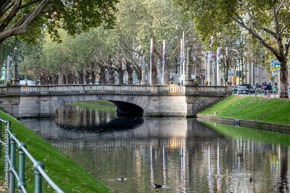 Düsseldorfer Königsallee im Spätsommer mit schöner Wasserspiegelung lädt zum Flanieren und Shoppen in der Modemetropole und Landeshauptstadt Düsseldorf ein