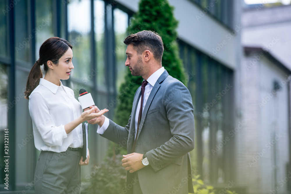 journalist holding microphone and talking with businesswoman in formal wear journalist holding microphone and talking with businesswoman in formal wear