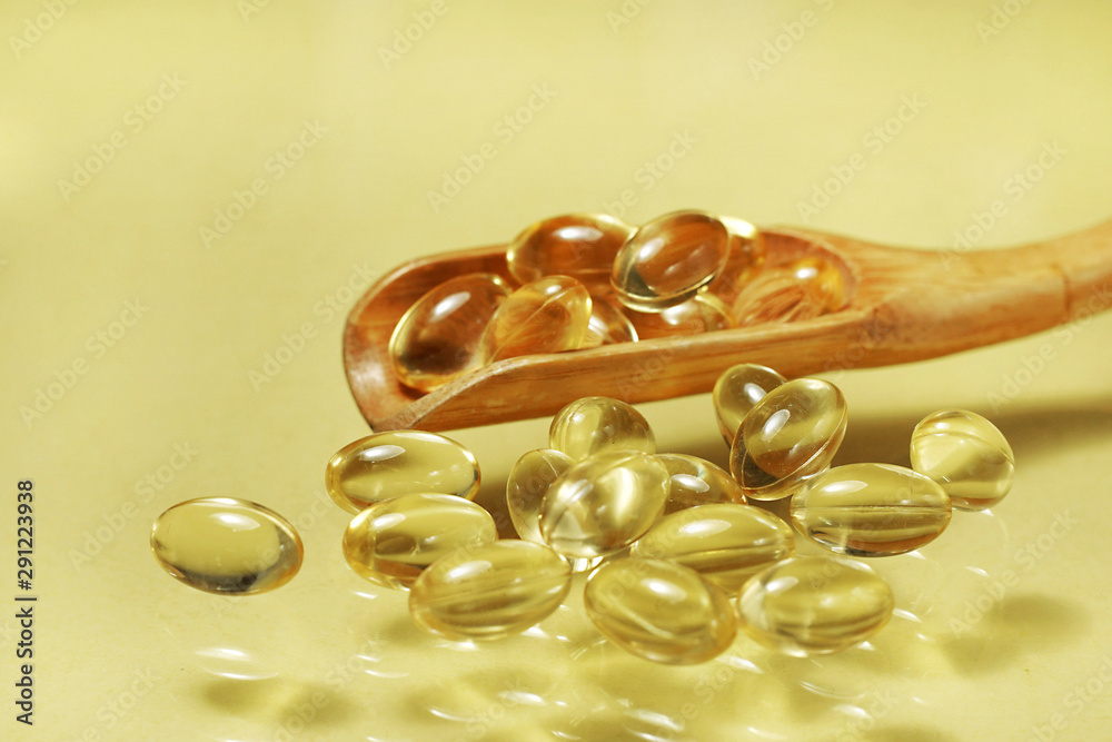 fish oil capsules isolated on yellow background fish oil capsules isolated on yellow background