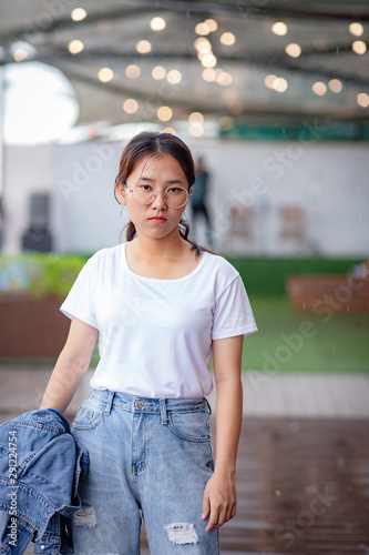 Nerdy Asian woman in white t-shirt and ripped jeans © AlivePhoto