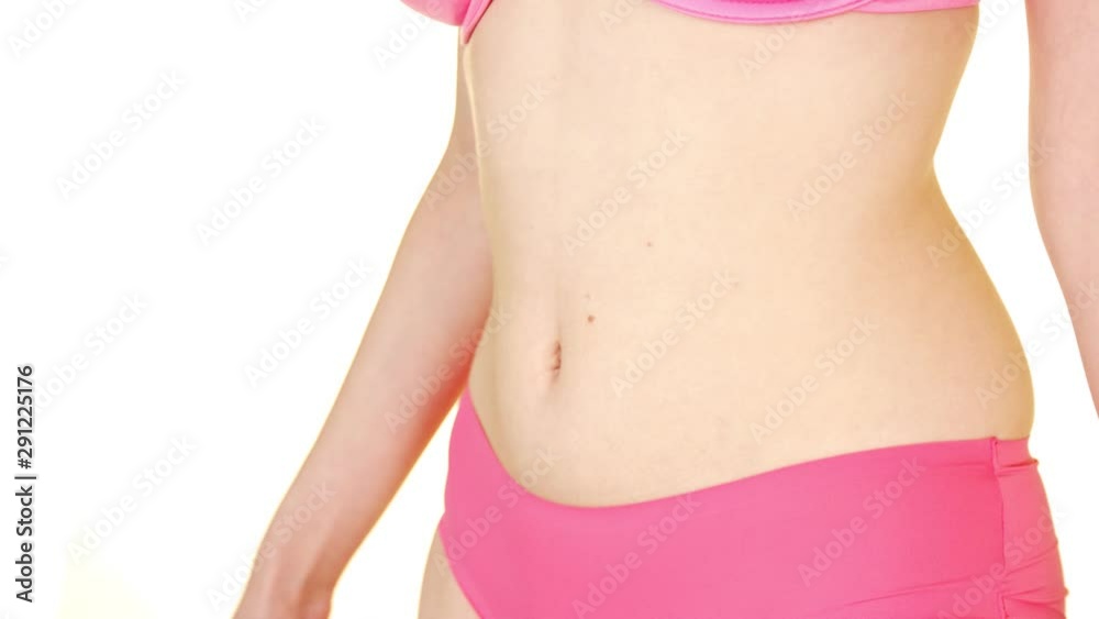 Close-up medium shot of a lady wearing pink lingerie and holding her stomach as if she has a tummy ache