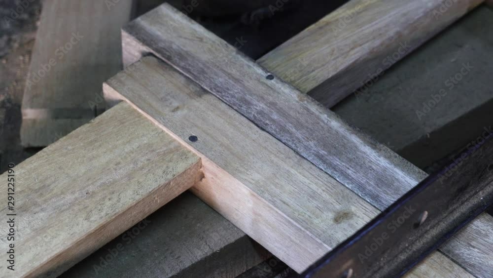 Carpenter fixing nails with a hammer on a wooden planks structure, closeup follow shot