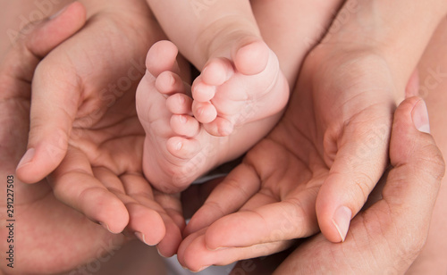 Hands of father and mother hold baby feet. Family