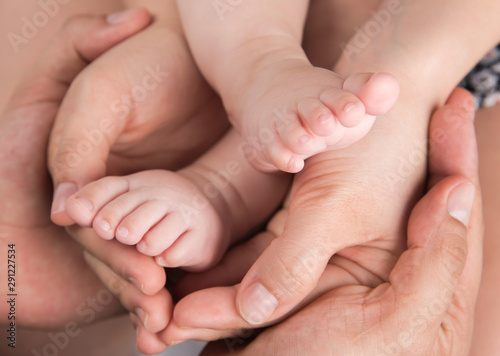 Hands of mother and father hold baby feet