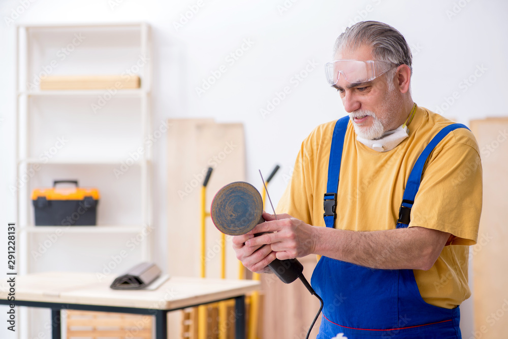 Old male carpenter working in workshop Old male carpenter working in workshop