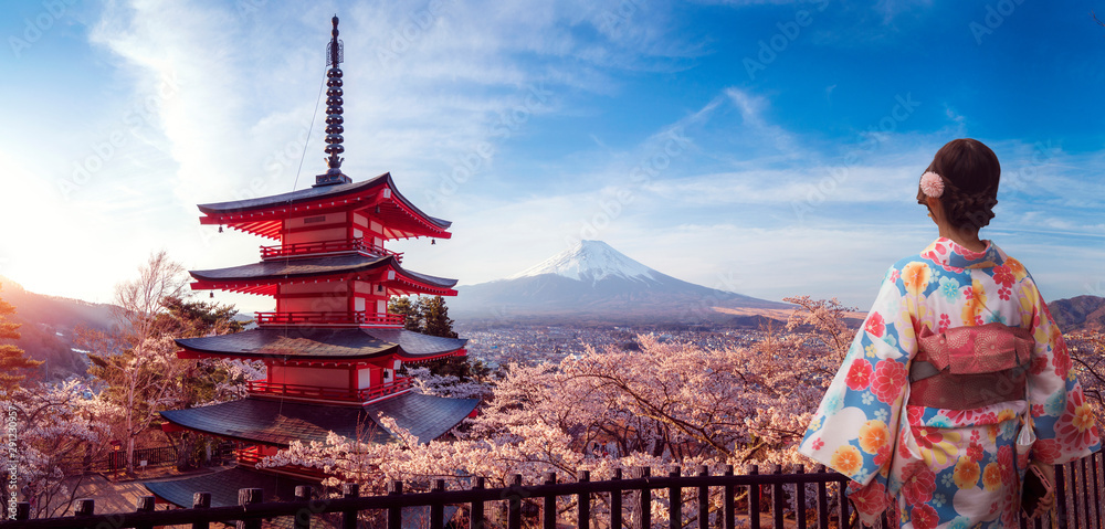 Naklejka premium Japonka w tradycyjnym stroju kimono spaceruje po parku Sakura na tle góry Fuji