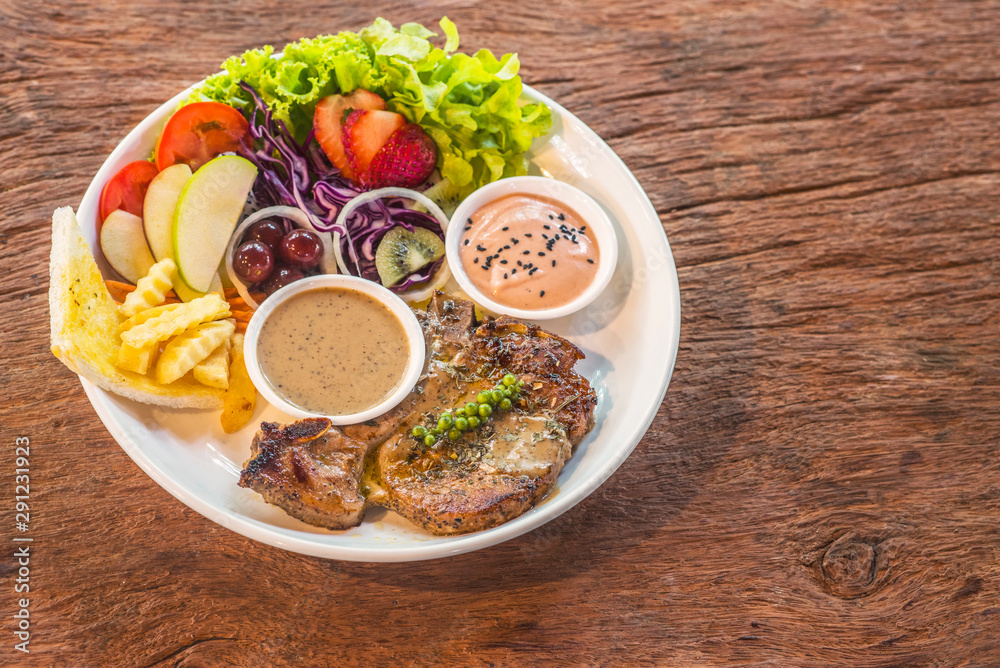 Steak topped with black pepper sauce on a white plate on a wooden table Steak topped with black pepper sauce on a white plate on a wooden table