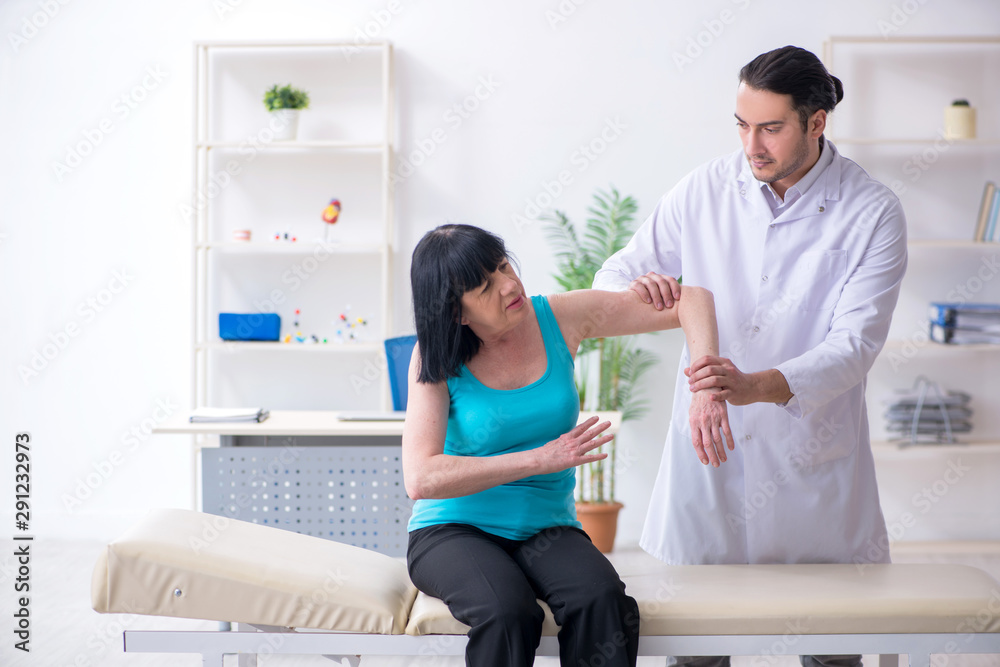 Fototapeta premium Young male doctor examining old female patient