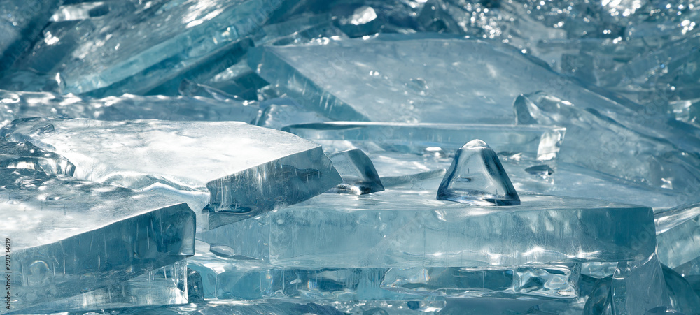 Luminous transparent broken ice blocks with beautiful structure, winter landscape in blue tones, wide format