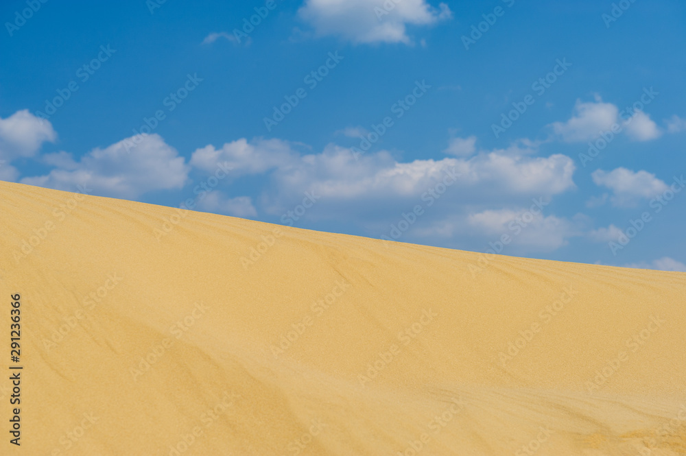 White clouds on a blue sky and dunes on a sunny day, landscape.