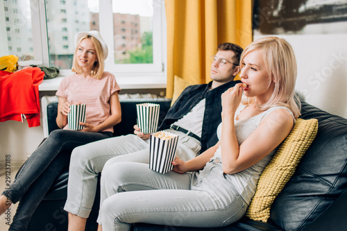 Cheerful group of friends eating popcorn at home © liliyabatyrova