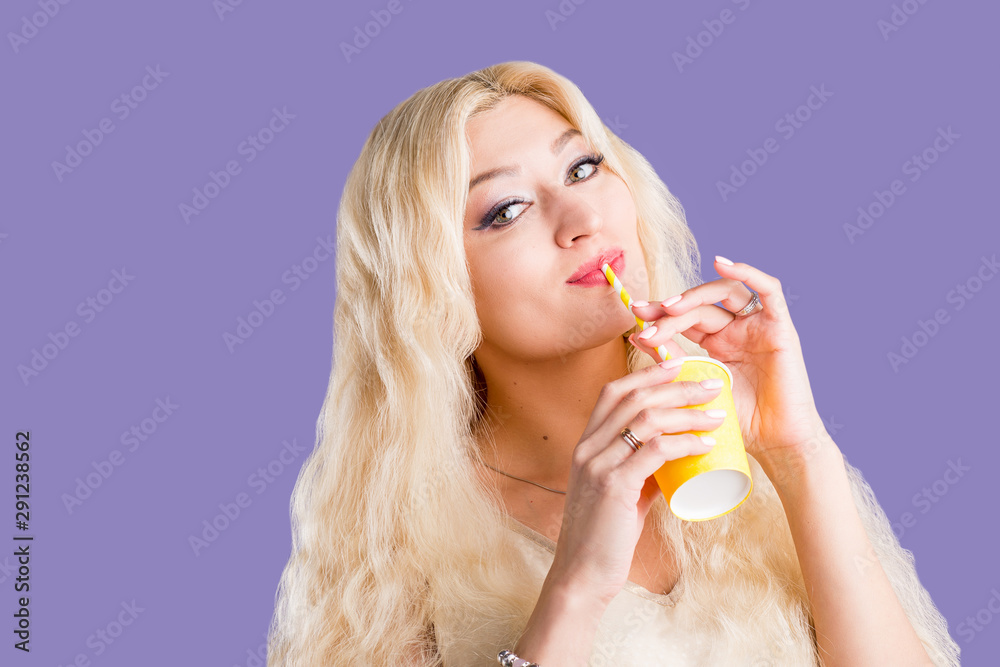 Beautiful woman on violet studio background drinking coffee in paper cup Beautiful woman on violet studio background drinking coffee in paper cup