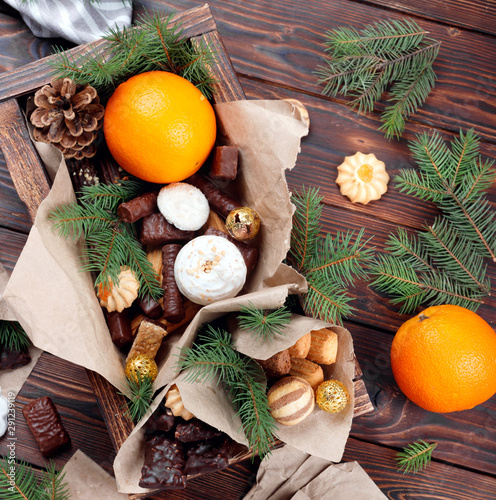 Delicious sweets, chocolates, cookies and oranges for gifts in wooden box on vintage table