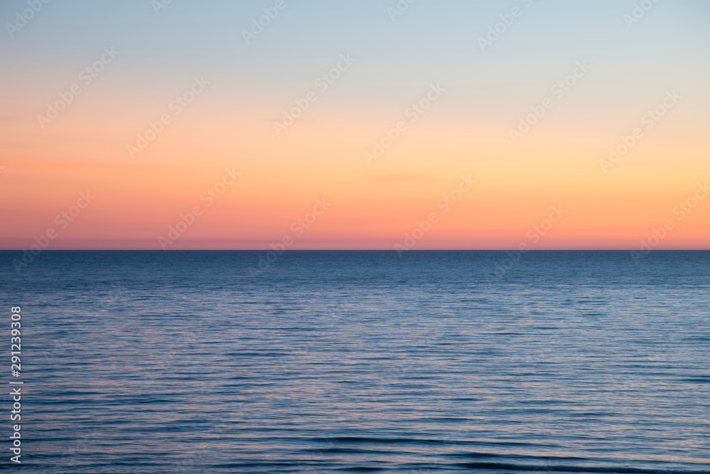 Beautiful Summer landscape sunset image of colorful vibrant sky over calm long exposure sea
