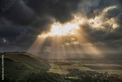 Stunning Summer landscape image of escarpment with dramatic storm clouds and sun beams streaming down photo