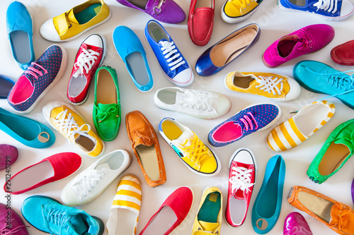 A lot of colored youth women's shoes without heels. Sneakers, slippers, ballet shoes. White background.